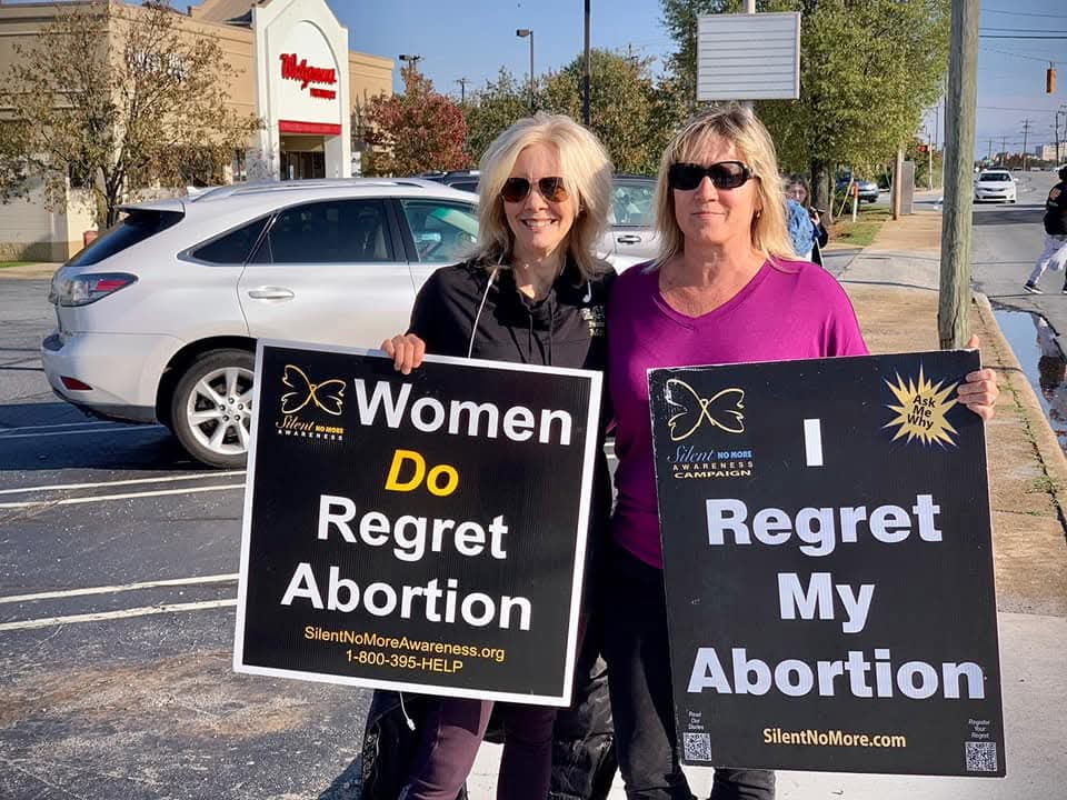 photo of two women holding up regret abortion signs